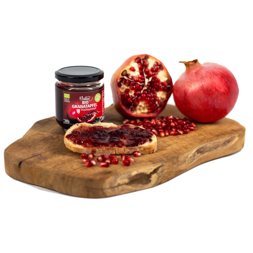 Granatapfel Fruchtaufstrich auf Brot dekorativ auf einem Holzbrett angerichtet mit Granatäpfeln und Kernen