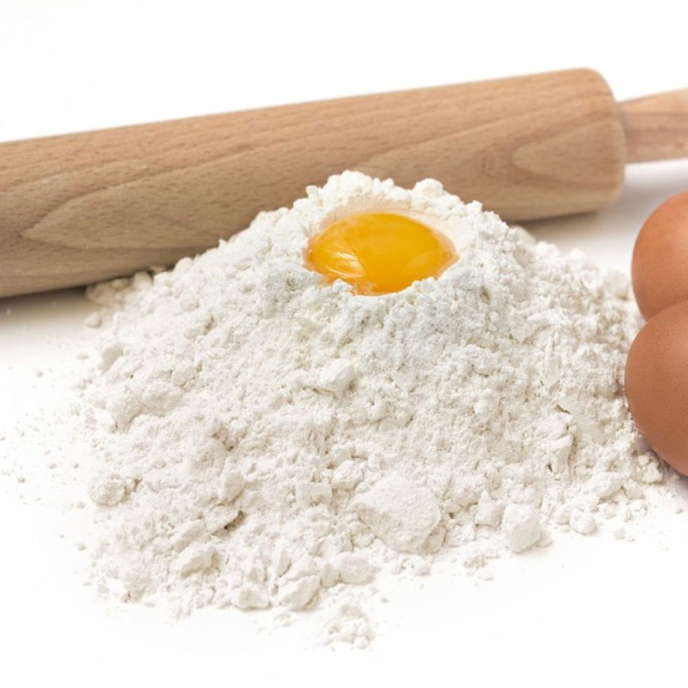 Helles Mehl zum Backen dargestellt mit Eiern und Nudelholz